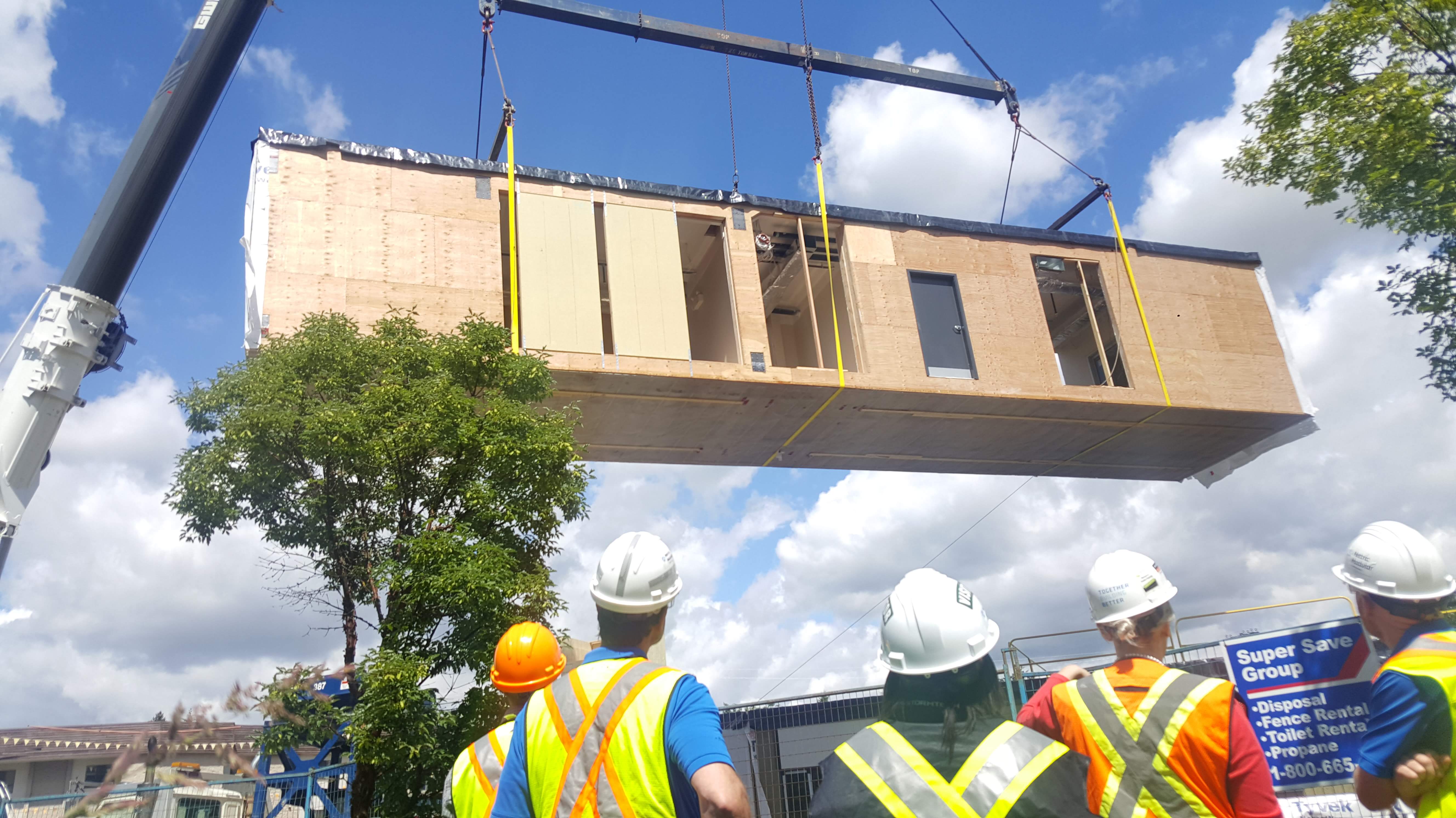 Workers look on as a crane operator lifts a prefabricated section of a new 220-bed dormitory at Trinity Western University. Photo courtesy Black Box Offsite Solutions.